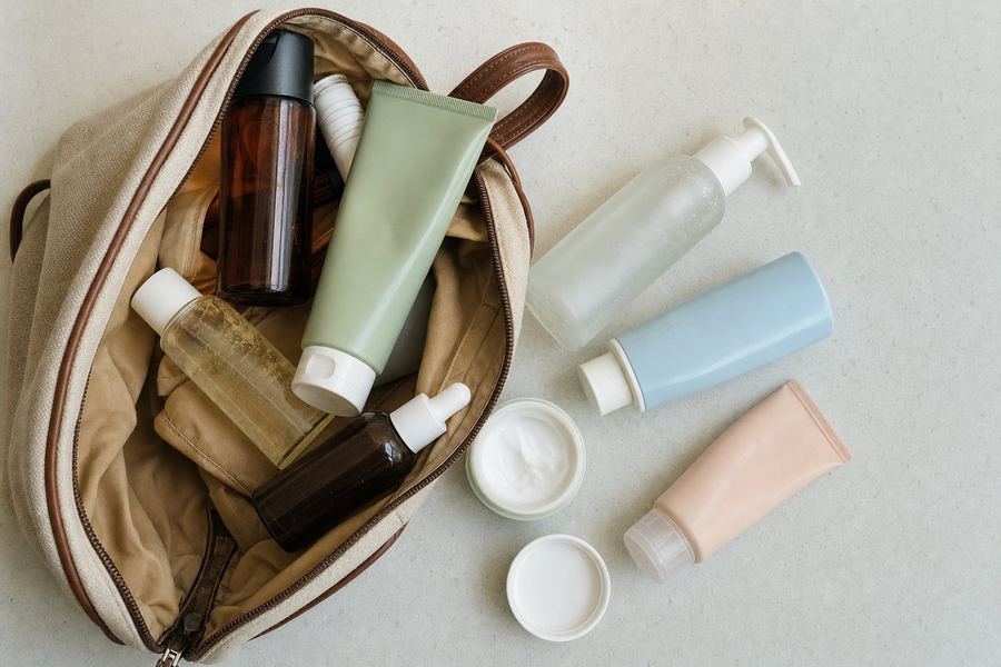 A cluttered toiletry bag with six mismatched travel bottles spilling out